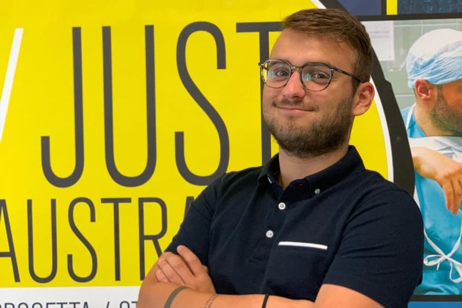 Just Australia team member in front of their yellow brand sign — from justaustralia.it